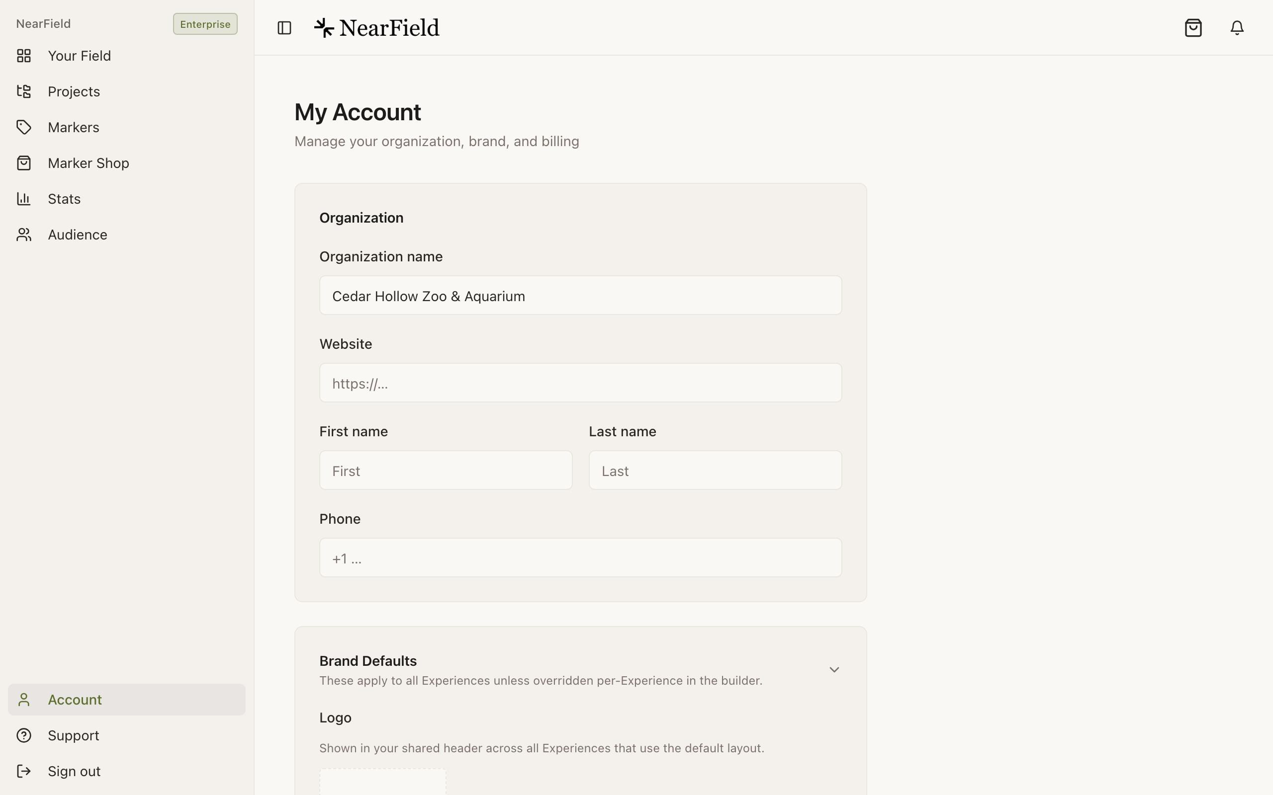 The top of the My Account page, subtitled "Manage your organization, brand, and billing". An Organization card holds an Organization name field filled with "Cedar Hollow Zoo & Aquarium", an empty Website field, First name and Last name fields side by side, and a Phone field. A Brand Defaults card begins below, noting that these apply to all Experiences unless overridden per-Experience in the builder, with a Logo upload described as shown in the shared header.
