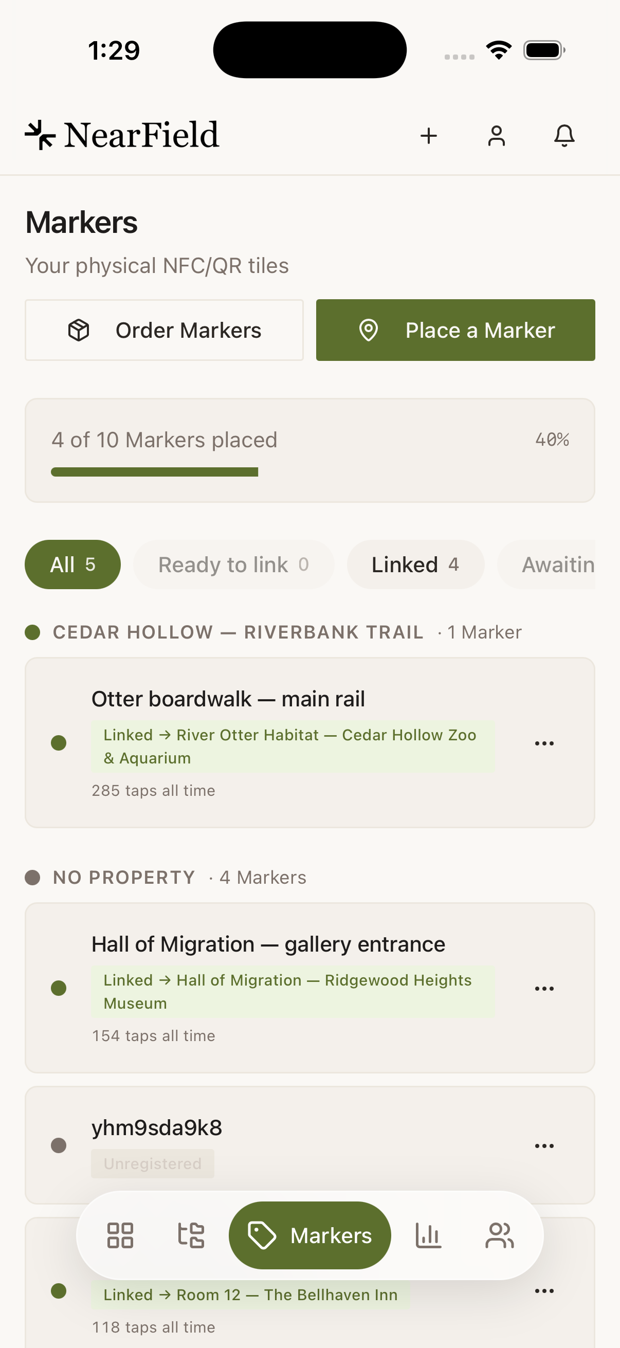 The Markers tab in the app. Order Markers and Place a Marker buttons sit above a meter reading "4 of 10 Markers placed, 40%", then filter chips for All 5, Ready to link 0, Linked 4 and Awaiting PIN. Rows are grouped by property: under “CEDAR HOLLOW — RIVERBANK TRAIL”, "Otter boardwalk — main rail" carries a green chip reading "Linked to River Otter Habitat" and 285 taps all time; further down an unnamed Marker listed by its hash carries a grey Unregistered pill.